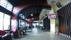 A spacious lobby with a high ceiling, decorative arches, and a seating area with wicker furniture.
