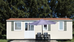 A single-story mobile home with a patio area, two chairs, and a table.
