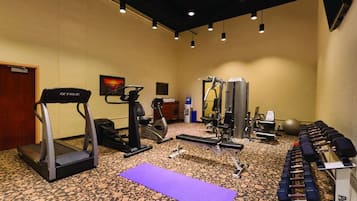 A gym with treadmills, weight machines, and dumbbells.