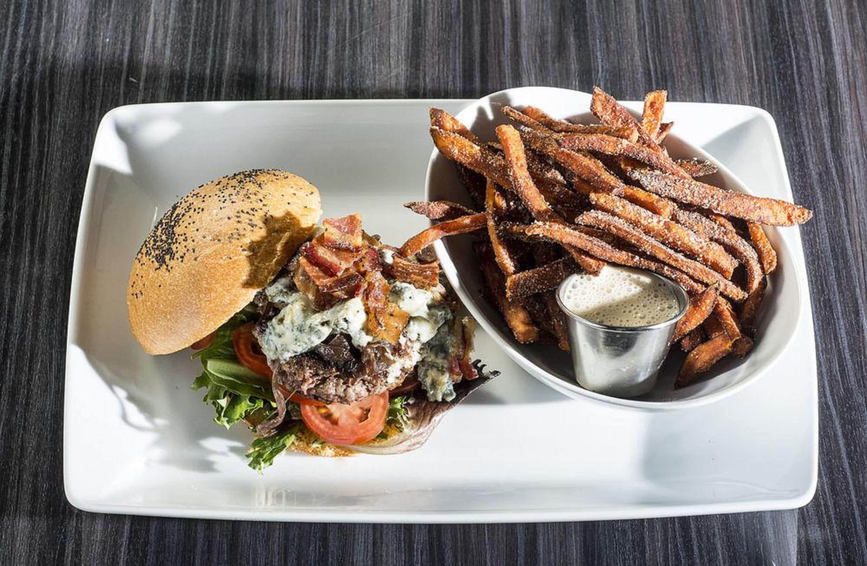 A plate with a burger, fries, and a side of sauce.
