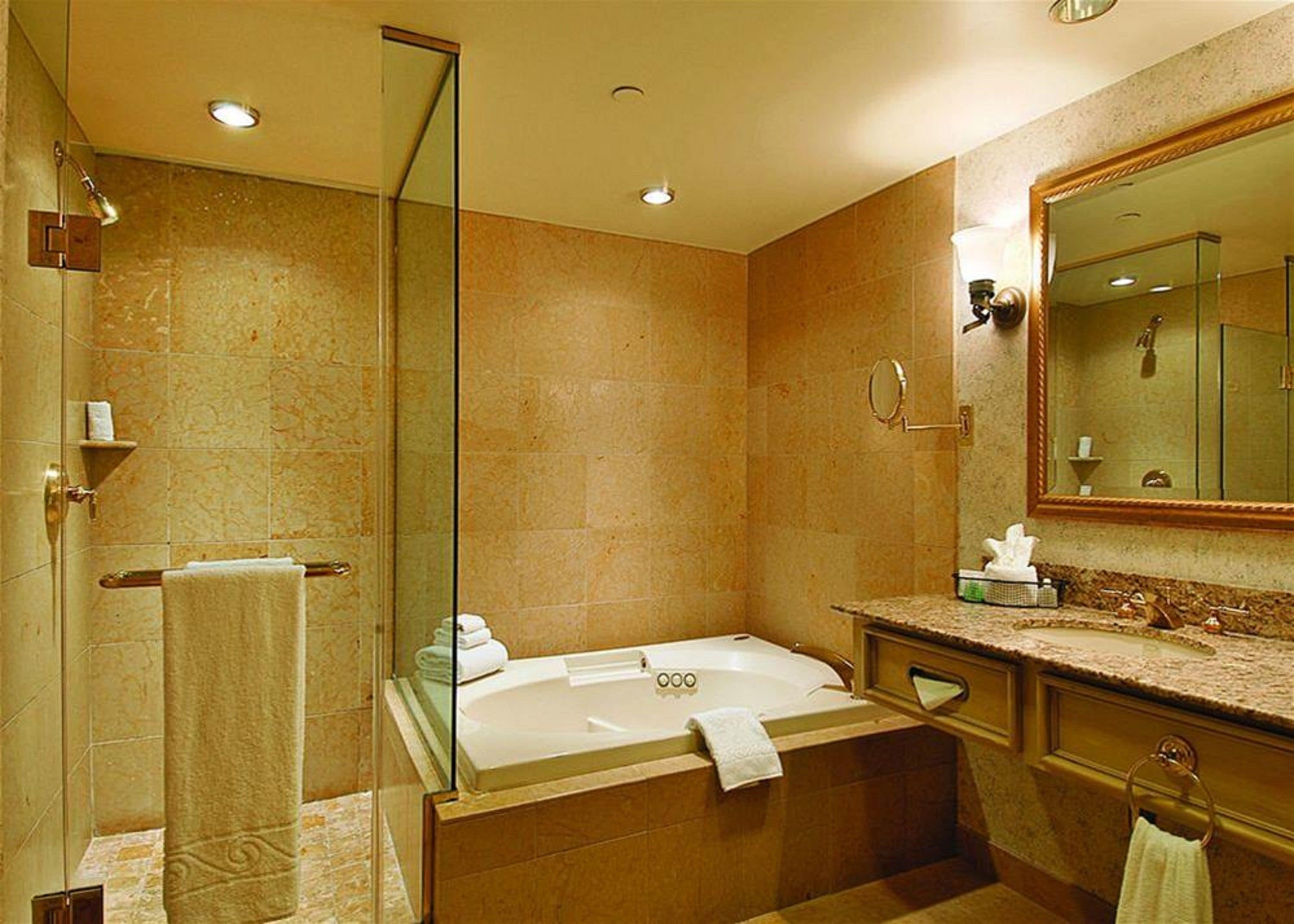 A modern bathroom with a glass shower enclosure, a freestanding bathtub, and a large mirror.