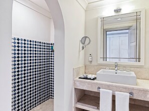 Un baño con lavamanos blanco, un espejo y pared con azulejos.