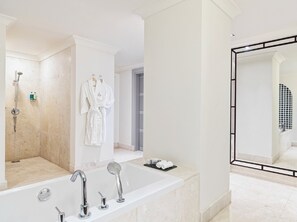 A modern bathroom with a large bathtub, a shower, and a walk-in closet. - Juweira Boutique Hotel (Salalah)