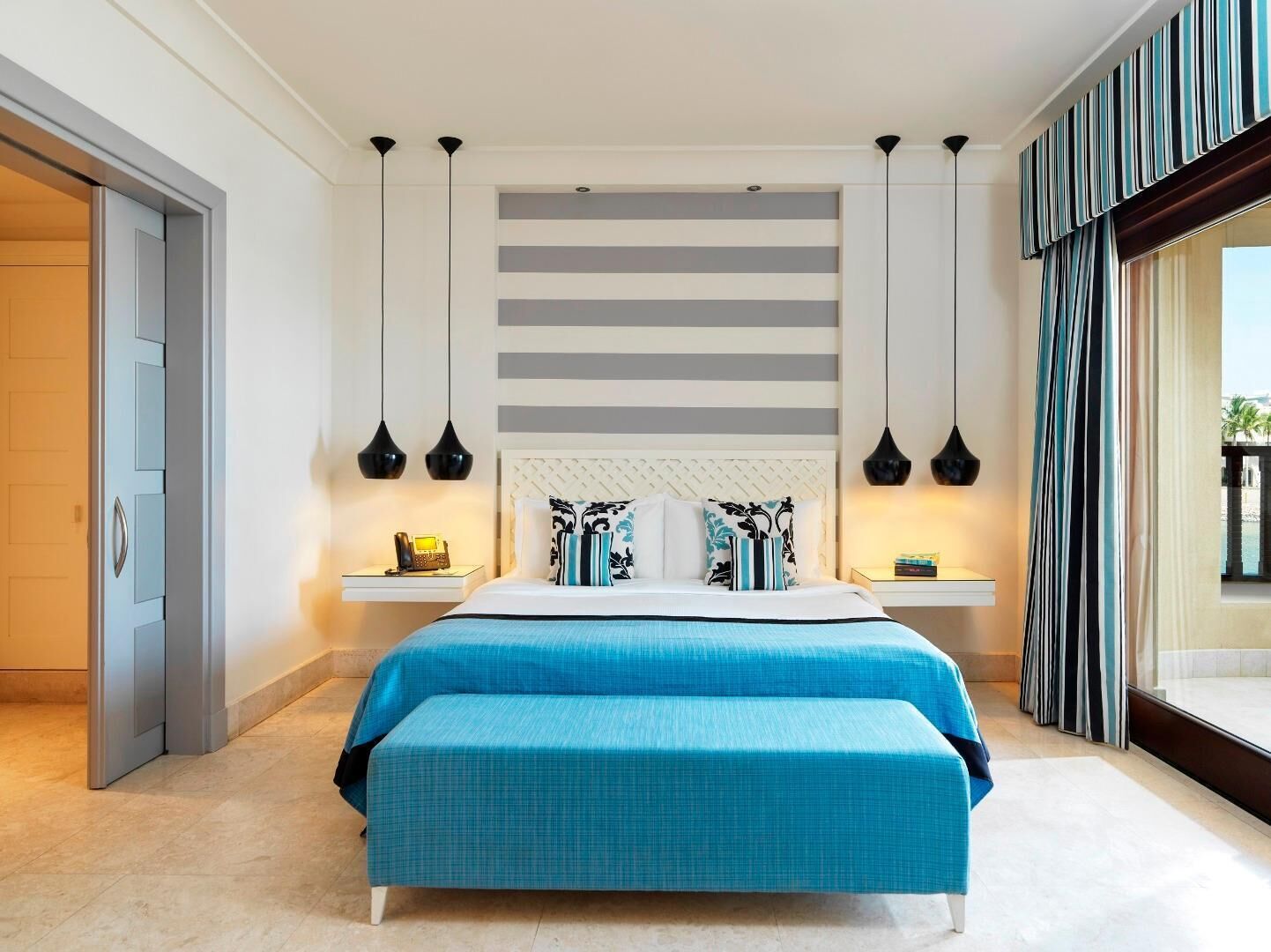 Ein modernes Schlafzimmer mit einem großen Bett, Nachttischen und Blick ins Freie.
