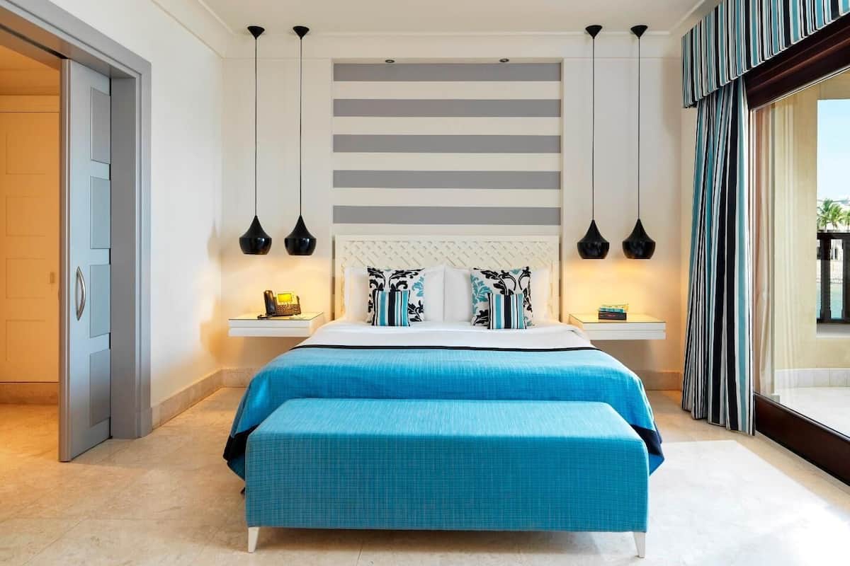 A modern bedroom with a large bed, bedside tables, and a view of the outdoors.