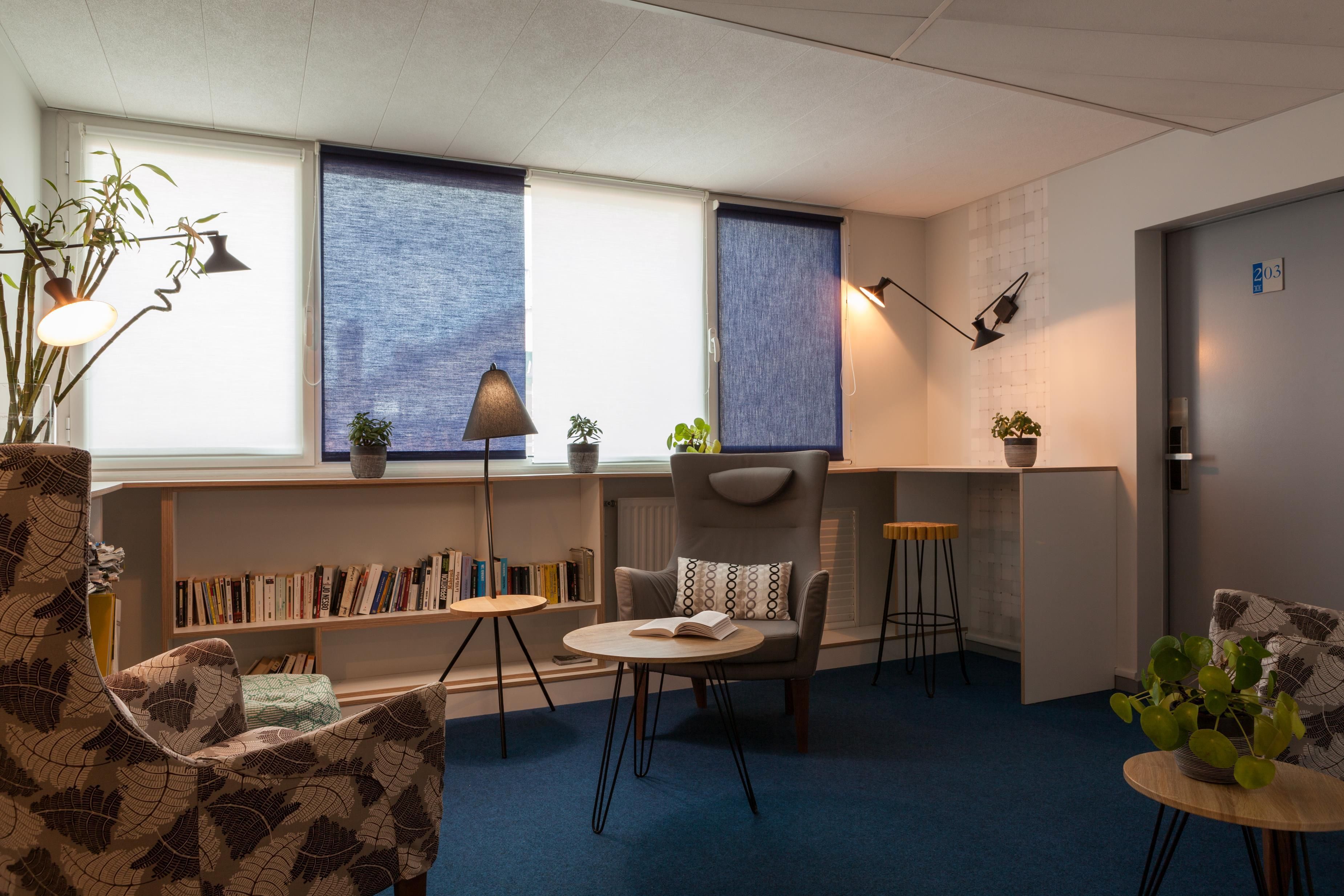 Una habitación moderna con estantería, escritorio, silla, mesa redonda y una planta en maceta.