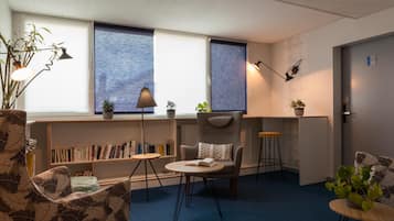 Una habitación moderna con estantería, escritorio, silla, mesa redonda y una planta en maceta.