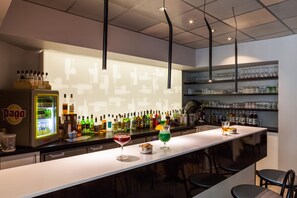 Un espace bar doté d’un long comptoir, d’étagères remplies de bouteilles et de verres.