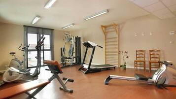 Une salle de sport équipée de machines de cardio, d’un tapis de course et d’un rameur.