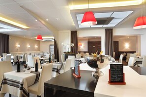 A restaurant with multiple dining tables, red pendant lights, and a menu stand. - The Originals City, Les Thermes de L'avenue, Dax (Dax)