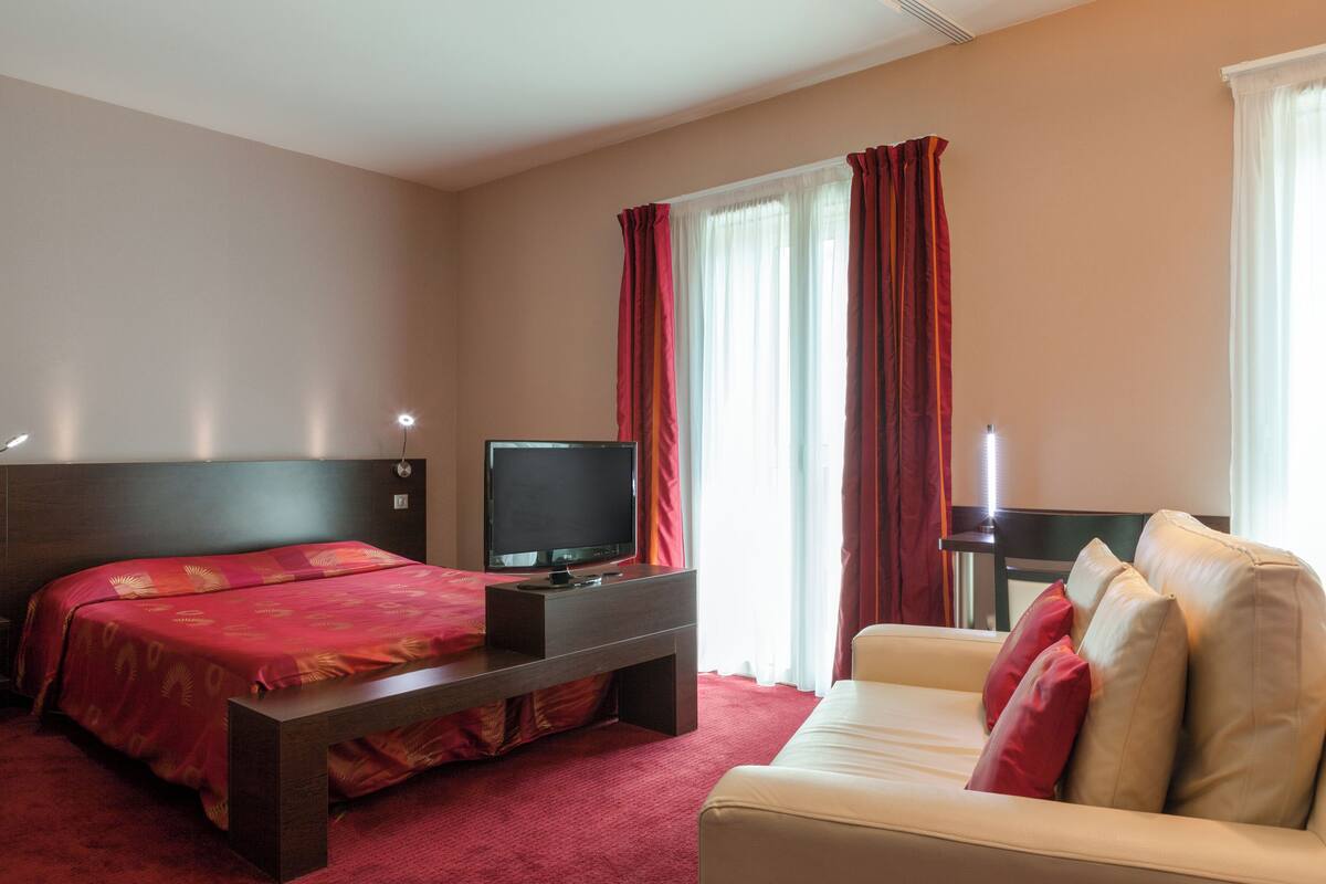 Une chambre d’hôtel équipée d’un lit, d’une télévision, d’un canapé et d’un bureau.
