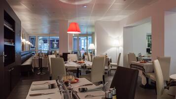 En restaurant med dækketøjet borde og rødt hængende lys, samt udsigt til gaden.