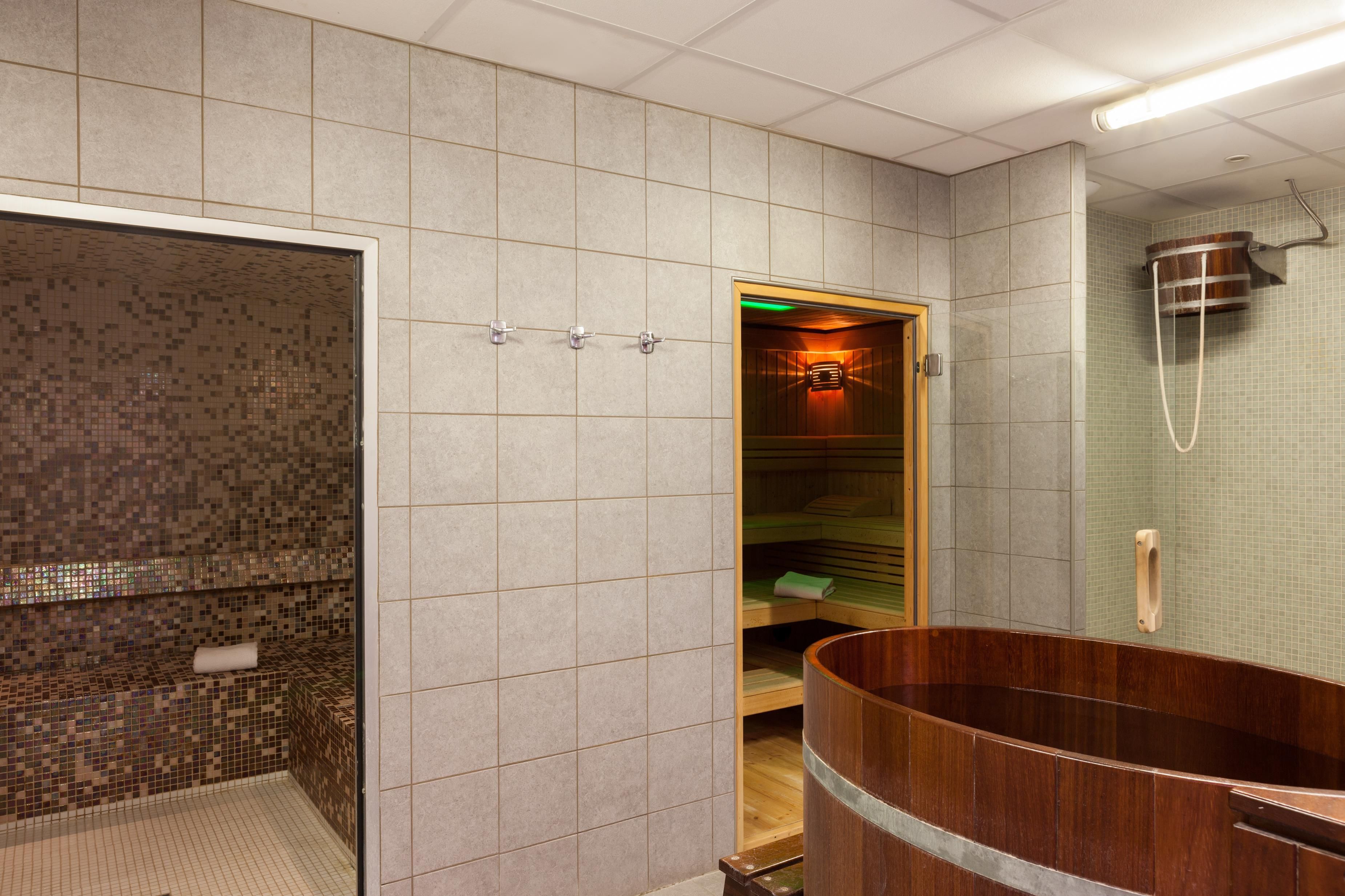 Un baño moderno con una bañera de madera grande, una zona de ducha separada y un muro con azulejos.
