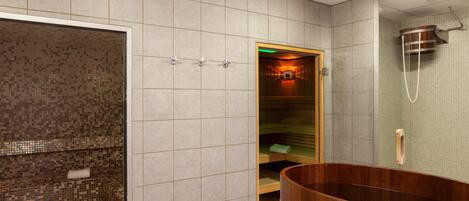 A modern bathroom with a large wooden bathtub, a separate shower area, and a tiled wall.