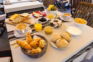 Een ontbijttafel met brood, gebak, fruit en drankjes.