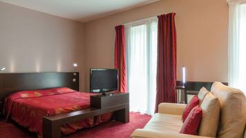 Una habitación de hotel con una cama, televisión, sofá y escritorio.