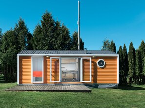 Une cabane moderne, de plain-pied, dotée d’une grande porte coulissante, d’un petit porche et d’une cheminée.