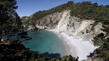 A coastal landscape with a beach, clear water, and rocky cliffs.