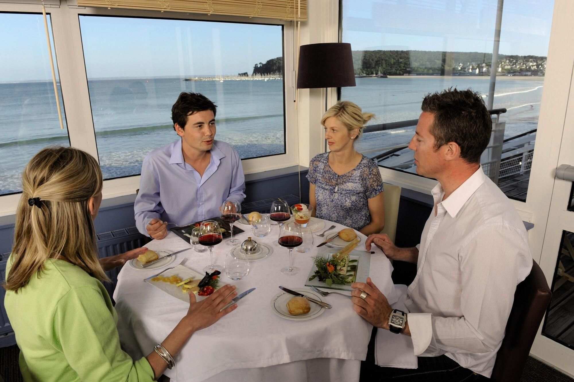 A group of people dining at a table with a view of the sea.