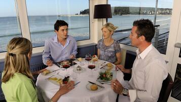 A group of people dining at a table with a view of the sea.