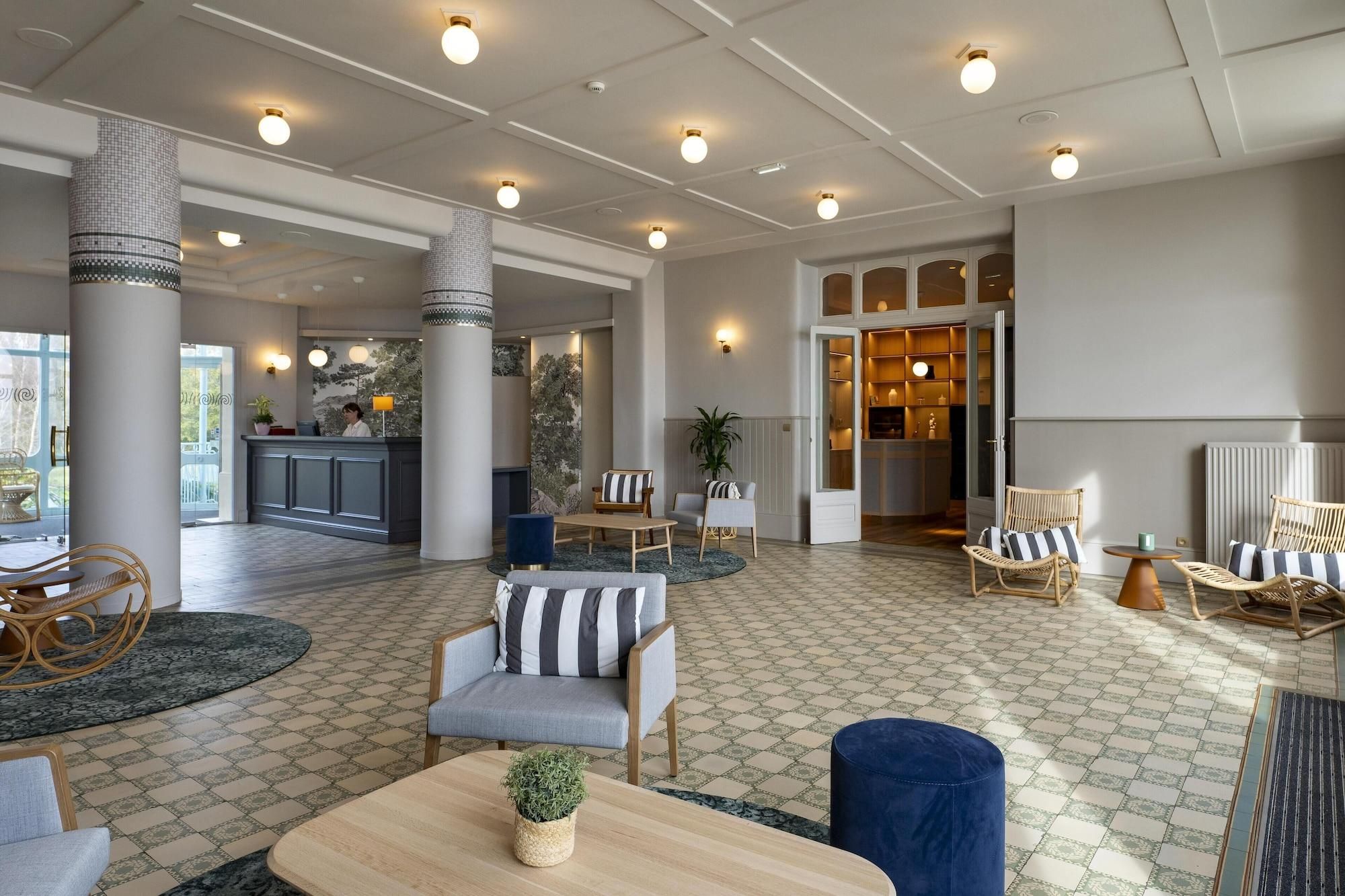 A spacious lobby with a reception desk, seating area, and a view of the kitchen.