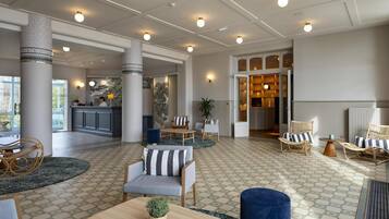 A spacious lobby with a reception desk, seating area, and a view of the kitchen.