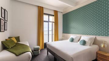 Una habitación de hotel con una cama, un sofá, una mesita redonda y una ventana con cortinas.