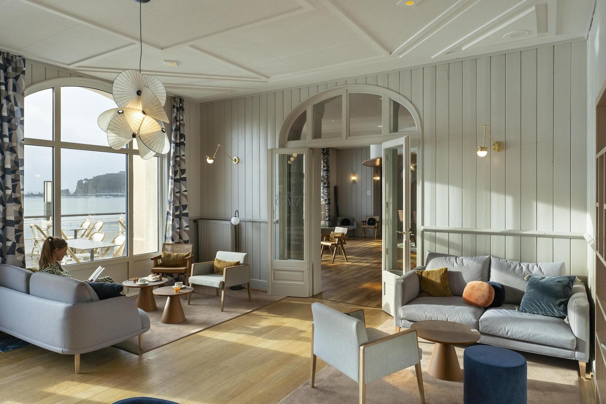 A spacious living area with a large window, a sofa, a coffee table, and a dining area with chairs.
