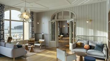 A spacious living area with a large window, a sofa, a coffee table, and a dining area with chairs.