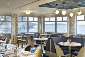 A restaurant with tables and chairs, large windows with a view of the sea, and a ceiling with recessed lighting. - Morgat "Le Grand Hôtel de la Mer" (Crozon)