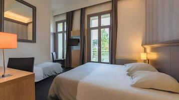 Een hotelkamer met twee bedden, een bureau, een stoel, een televisie en grote ramen.