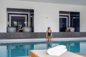 A person sitting by a pool with a towel on a table, a chair, and a small table with a vase of flowers. - Morgat "Le Grand Hôtel de la Mer" (Crozon)