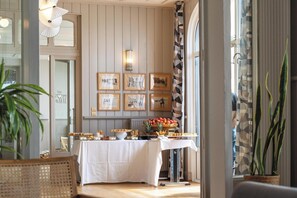 A dining area with a table set for a meal, framed pictures on the wall, and a plant in the foreground. - Morgat "Le Grand Hôtel de la Mer" (Crozon)