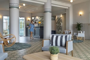 A lobby with a reception desk, seating area, and large columns.