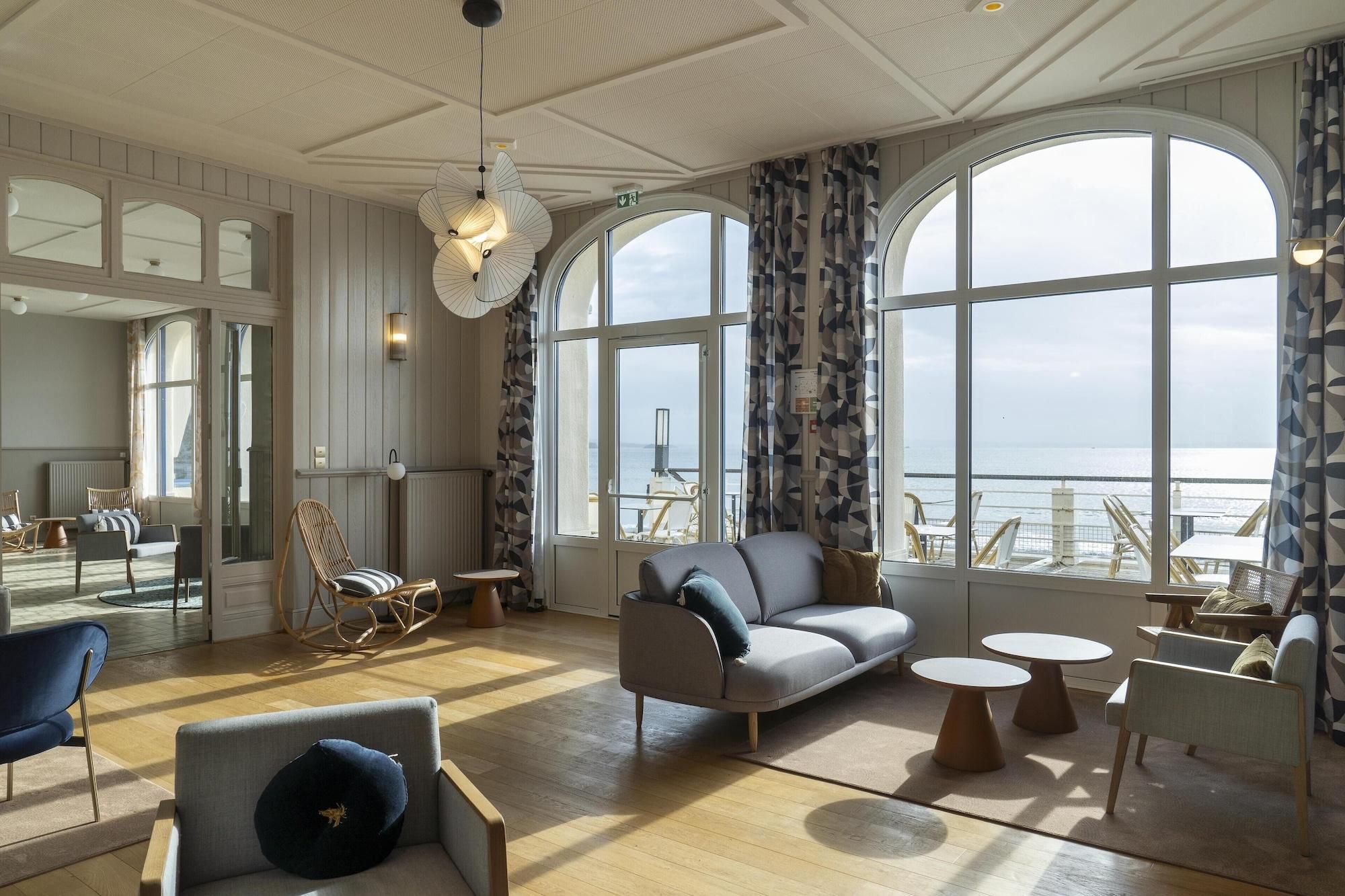 A spacious room with a large window, a sofa, a chair, and a small table.