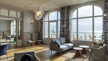 A spacious room with a large window, a sofa, a chair, and a small table.