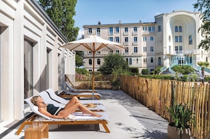 A hotel with a pool area featuring sun loungers and a wooden deck.