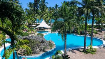 A resort with multiple swimming pools, palm trees, and a beach area.