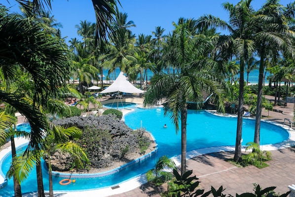 A resort with multiple swimming pools, palm trees, and a beach area.
