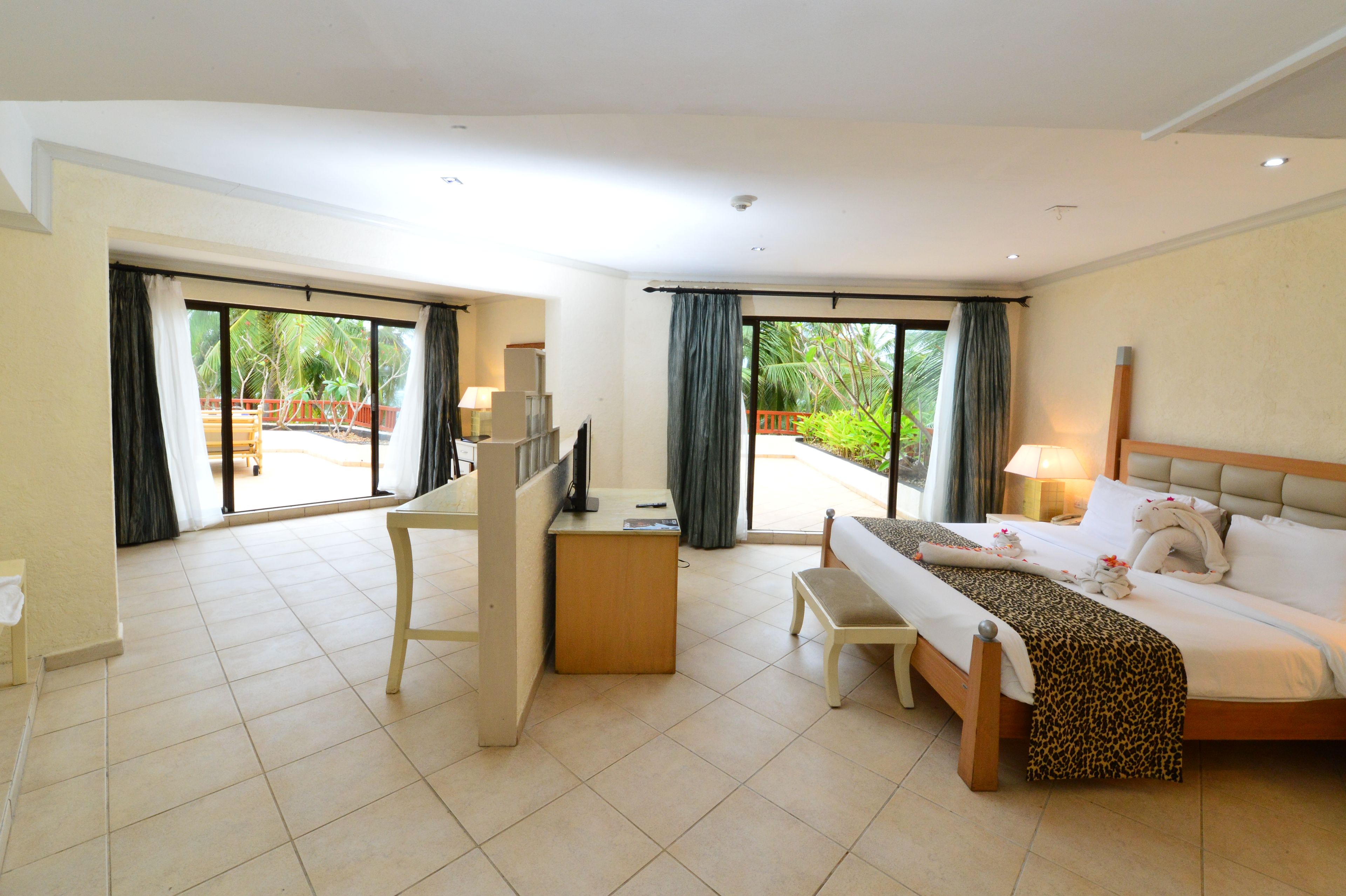 A hotel room with a bed, desk, and large sliding glass doors leading to a balcony.
