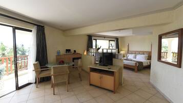 A hotel room with a balcony, a dining area, a TV, and a bed.