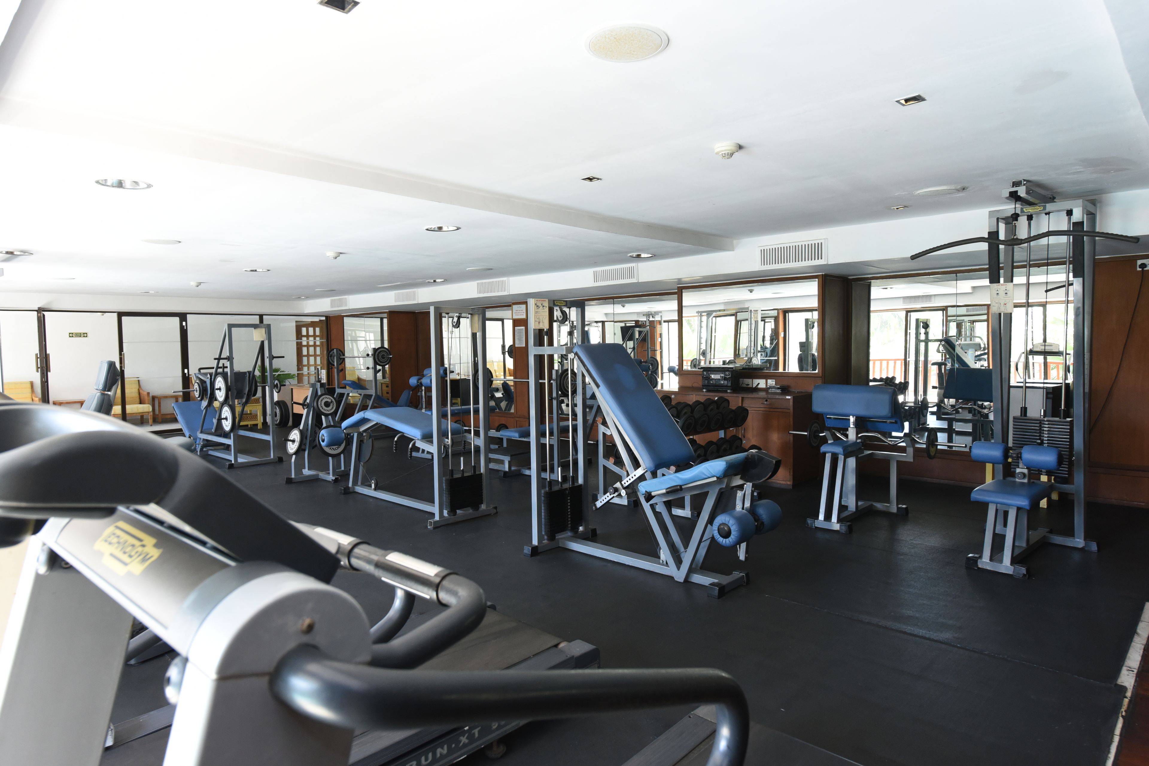 A gym with exercise equipment, mirrors, and a treadmill.