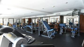 A gym with exercise equipment, mirrors, and a treadmill.