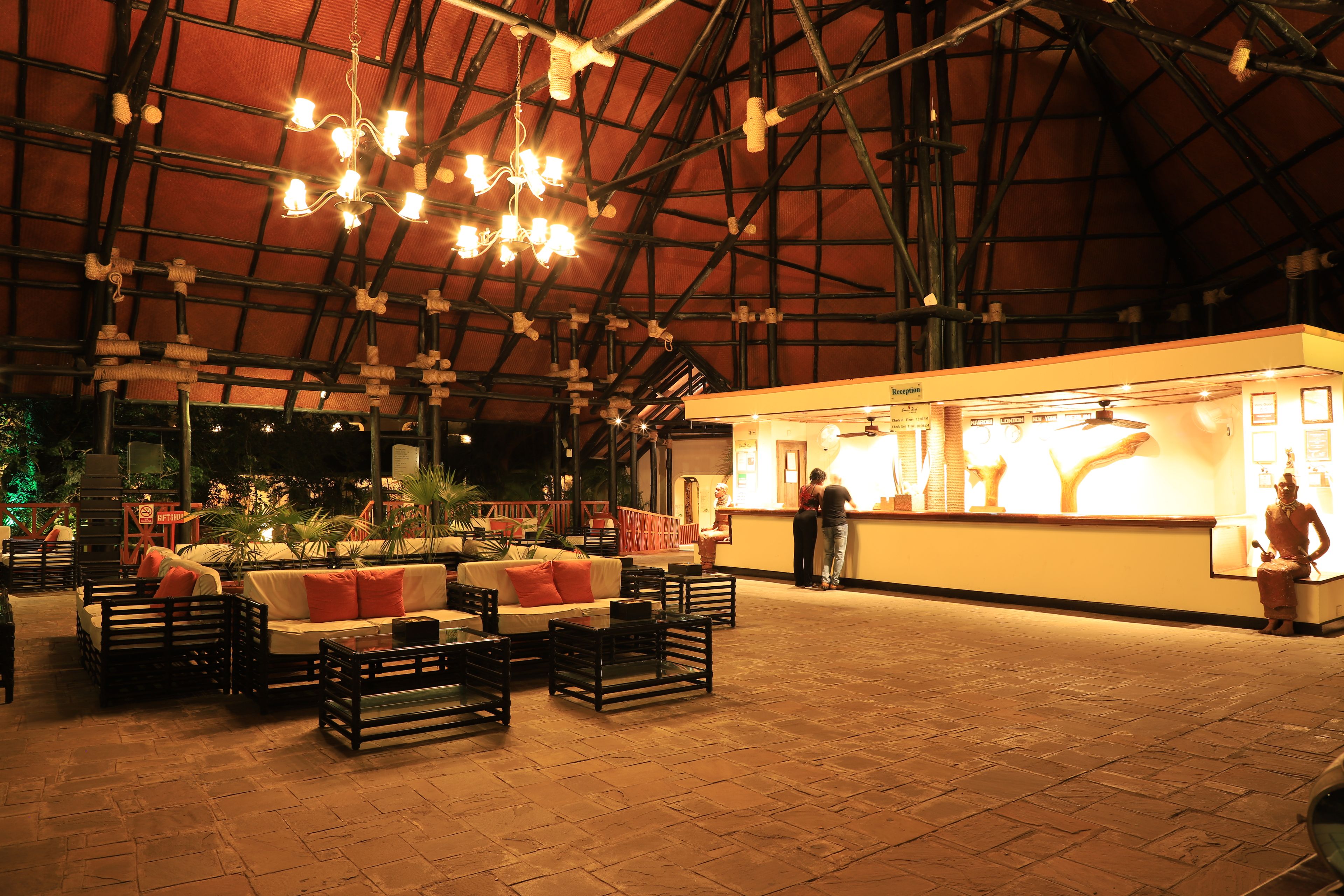 An indoor space with a high ceiling, wooden beams, and a seating area with sofas and tables.