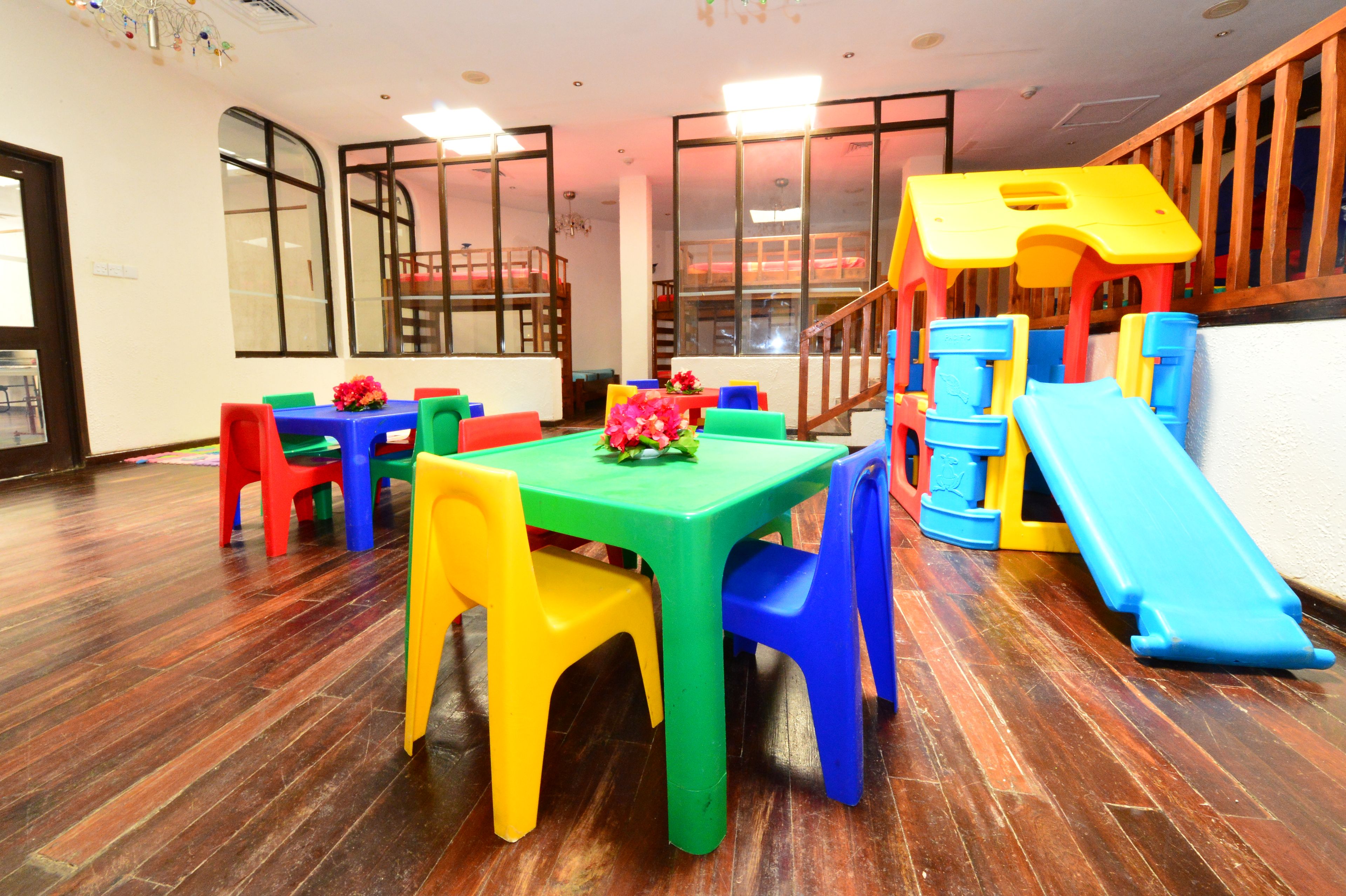 A children's play area with a slide, colorful plastic furniture, and a wooden floor.