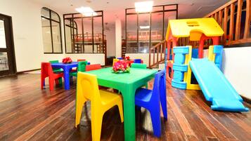 A children's play area with a slide, colorful plastic furniture, and a wooden floor.