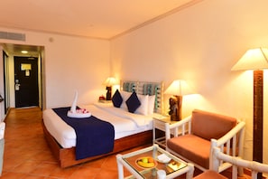 A hotel room with a bed, a chair, a small table with fruit, and two lamps. - Diani Reef Beach Resort & Spa (Diani Beach)