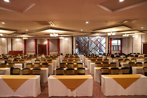 A conference room with rows of tables and chairs, large windows, and a red curtain. - Diani Reef Beach Resort & Spa (Diani Beach)