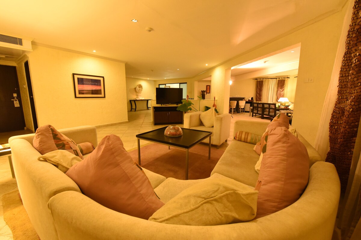 A living room with a sofa, armchairs, a coffee table, and a TV.