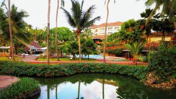 A resort with a swimming pool, palm trees, and a building with a red roof.